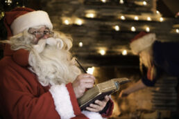 Santa Claus writes in his old book by the fire in his cabin, a Christmas visit for Arcora guests in Muonio, Lapland.